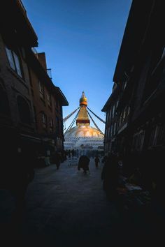 people walking down the street in front of a large building with a golden dome on top