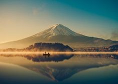 a person on a boat in the water with a mountain in the backgroud