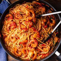 pasta with shrimp and tomato sauce in a skillet on a wooden counter top, ready to be eaten