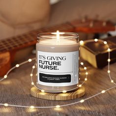 a lit candle sitting on top of a wooden table next to a string of lights