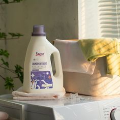 a bottle of laundry deterant sitting on top of a dryer next to towels