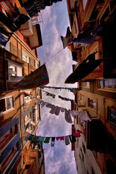 the sky is reflected in an alleyway with laundry hanging from it's sides