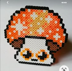 an orange and white beaded brooch sitting on top of a table next to a computer mouse