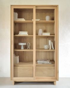 a wooden bookcase filled with books on top of a white floor next to a wall