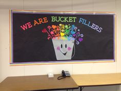 there is a sign that says we are bucket fillers on the blackboard in front of two desks