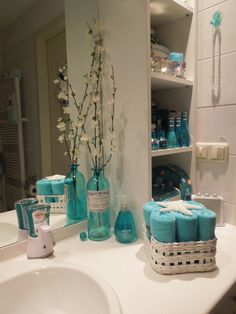 a bathroom sink with blue towels and vases on it