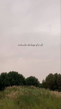 the sky is very cloudy and there are trees in the field with an inspirational quote on it