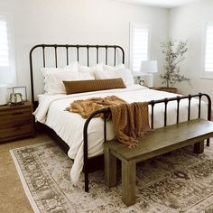 a bedroom with a bed, bench and rug on the floor in front of it