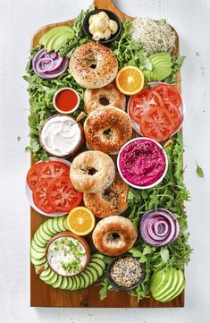 a wooden cutting board topped with donuts and salads covered in toppings next to sliced avocado