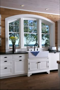 a kitchen with white cabinets and an arched window over the sink is pictured in this image