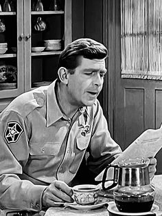 a man in uniform sitting at a table with a pot and pan on top of it