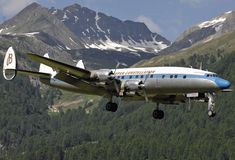 an airplane is flying low to the ground with mountains in the background