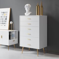 a white chest of drawers next to a gold and white busturine on the wall