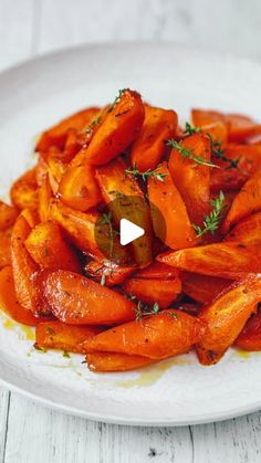 a white plate topped with cooked carrots and herbs