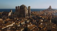 an aerial view of a city next to the ocean with old buildings and large towers