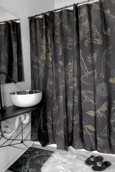 a black and white photo of a bathroom with shower curtain, rugs and sink