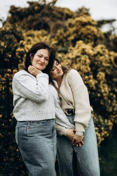 two women standing next to each other with their arms around one another and looking at the camera