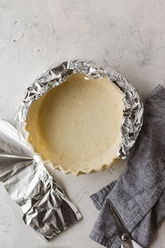 an uncooked pie sitting on top of a table next to some napkins