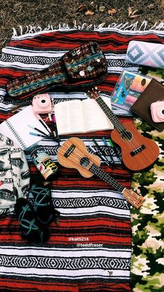 an assortment of musical instruments laid out on a blanket with books and other items around it