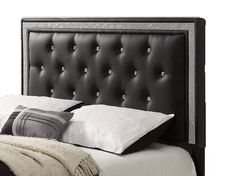 a black headboard with white pillows and two pictures on the wall in the background