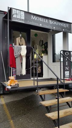 a mobile boutique with stairs leading up to the door and clothes on display in it