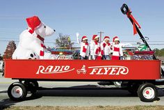 the radio flyer wagon is full of people dressed as santa claus and a white dog