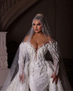 a woman in a white wedding gown with long sleeves and a veil on her head