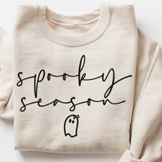 a white sweatshirt with the words spooky season written on it in black ink