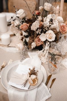 the table is set with white and gold plates, silverware, napkins, and flowers