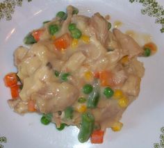 a white plate topped with meat and veggies covered in gravy on top of a table