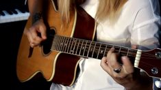 a woman playing an acoustic guitar in front of a piano