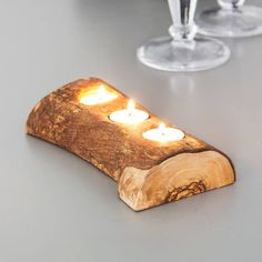 three lit candles are placed on a piece of wood that has been carved into the shape of a log