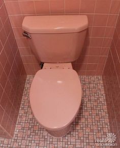 a pink toilet in a tiled bathroom stall