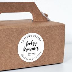 a brown box with a white sticker on the lid that says, lauren's bakery budy brownes