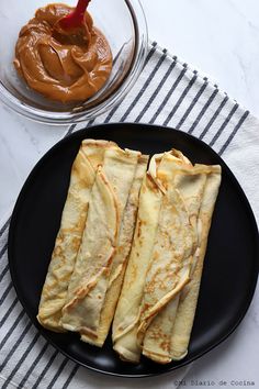 two crepes on a black plate with peanut butter