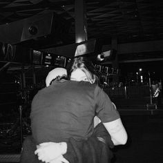 black and white photograph of two people hugging each other in an airport terminal at night