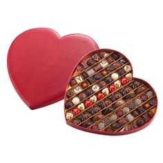 a heart shaped box filled with chocolates on top of a white table next to a red container