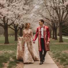 a man and woman walking down a sidewalk in front of trees with blossoming branches