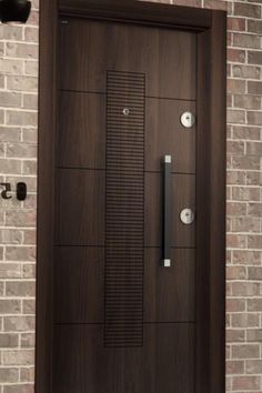 a wooden door with metal handles on a brick wall in front of a light fixture