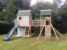 a wooden play set in the middle of a yard with a slide and climbing frame