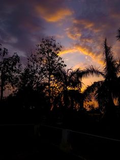 the sun is setting behind some trees and clouds in the sky with no one visible