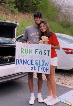 a man and woman standing next to a car holding a sign that says run fast but can't slow with me at prom