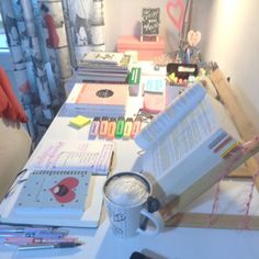 a table with many different items on it and a cup sitting next to the desk