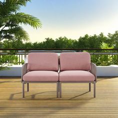 two pink chairs sitting on top of a wooden floor next to a palm tree in front of a balcony