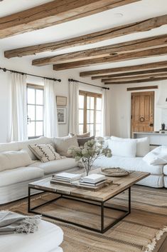 a living room filled with white furniture and wooden beams