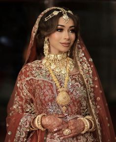 a woman wearing a red and gold bridal outfit