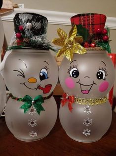 two frosty snowmen with hats and bows on their heads sitting next to each other