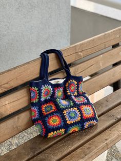 a crocheted bag sitting on top of a wooden bench