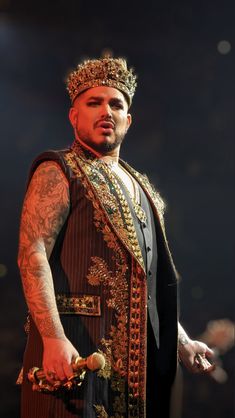 a man wearing a crown and holding a bottle in his hand while standing on stage