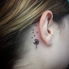 a woman's behind the ear has a small tree tattoo on it